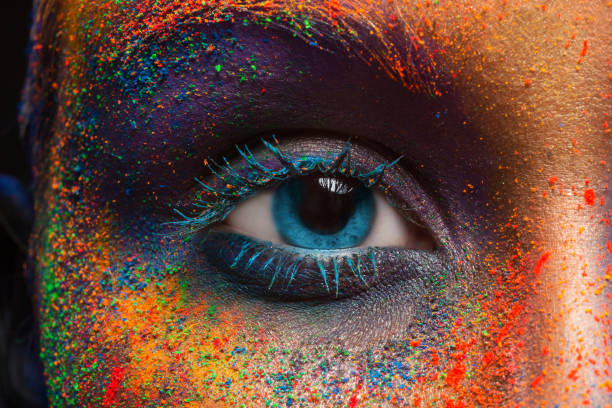 Close-up of a blue eye with colorful powder on the face